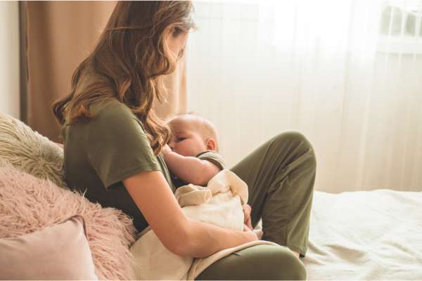 Woman breastfeeding her baby with the assistance of a human lactation specialist