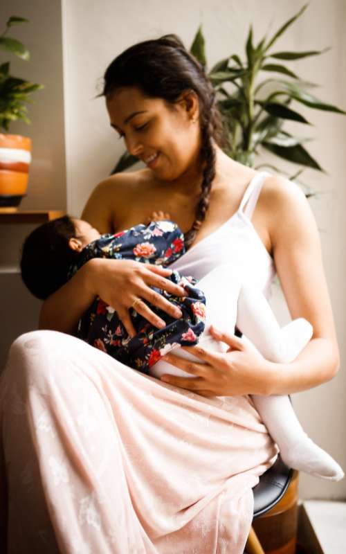 Mother breastfeeding newborn baby with help of a lactation consultant certified from the OHSU-PSU School of Public Health Lactation Program