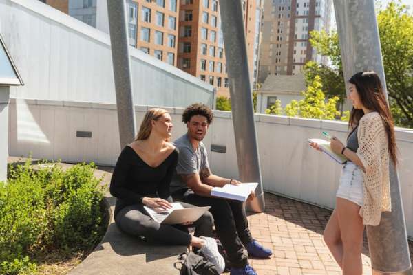 Undergraduate PSU students studying outside on a patio with their notebooks and laptops in downtown Portland