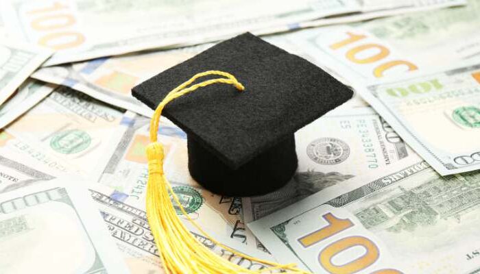PSU Graduation Cap on a pile of 100 dollar bills