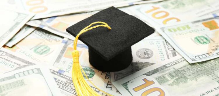 PSU Graduation Cap on a pile of 100 dollar bills