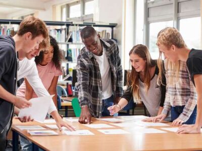 OHSU-PSU School of Public Health undergraduate students stand above a table in the PSU library discussing a public health journal article