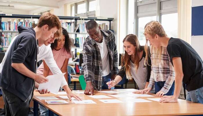 OHSU-PSU School of Public Health undergraduate students stand above a table in the PSU library discussing a public health journal article