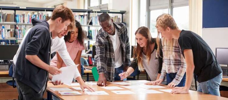 OHSU-PSU School of Public Health undergraduate students stand above a table in the PSU library discussing a public health journal article