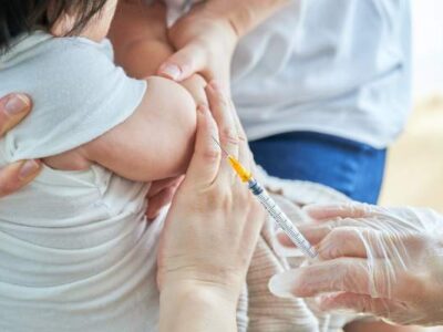 Baby getting a Hepatitis B Vaccination while being held by their parent and nurse at a clinic in Portland, OR