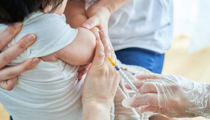 Baby getting a Hepatitis B Vaccination while being held by their parent and nurse at a clinic in Portland, OR