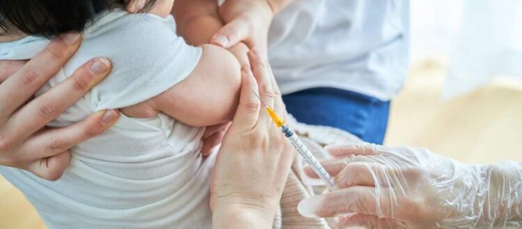 Baby getting a Hepatitis B Vaccination while being held by their parent and nurse at a clinic in Portland, OR